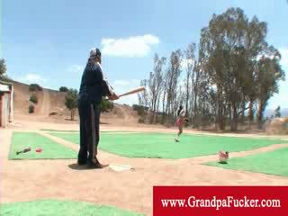 Old man showing a lady how to swing